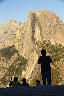 Half Dome at dusk from Glacier Point above Yosemite Valley, California, USA, with tourists.