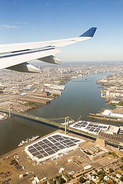 Approaching Philadelphia, over the Benjamic Franklin Bridge on the Delaware River, with harbour front warehouses covered in solar panels. USA.