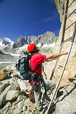 A mountaineer climbing the Egrelets ladders off the Mer Du Glace with Mont Blanc in the background above Chamonix, Haute Savoie, France, Europe