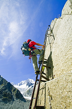 A mountaineer climbing the Egrelets ladders off the Mer Du Glace with Mont Blanc in the background above Chamonix, Haute Savoie, France, Europe