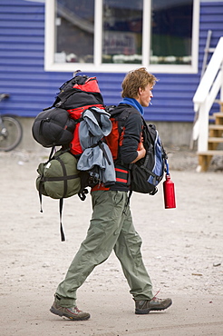 Traveller weighed down with heavy rucksacks in Ilulissat, Greenland, Polar Regions