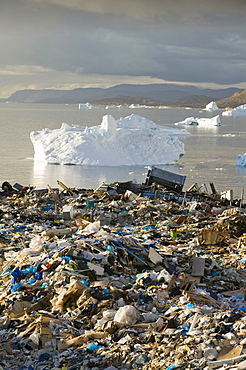 Rubbish dumped on the tundra outside Ilulissat in Greenland with icebergs behind from the Sermeq Kujalleq (Ilulissat Ice fjord), a UNESCO World Heritage Site, Greenland, Polar Regions