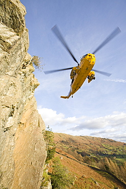 An RAF Sea King helicopter evacuates a seriuosly injured climber with a broken femur from a mountain rescue site in the Langdale Valley, Lake District, England, United Kingdom, Europe