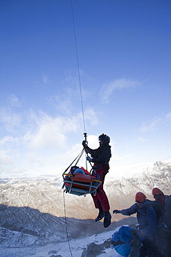 A Navy Sea King helicopter crew and mountain rescue team members treat a seriously injured walker who had fallen 250 , Cumbria, England, United Kingdom, Europe