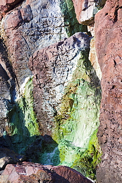 Sea cliffs stained green from copper deposits leaching from the old Geevor Tin Mine near St. Just in Cornwall, England, United Kingdom, Europe