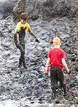 Children playing in a muddy creek at Blakeney, North Norfolk, England, United Kingdom, Europe