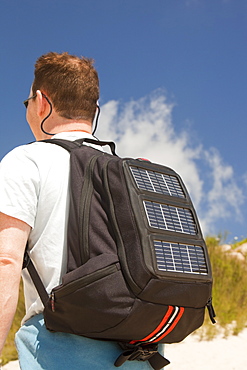 A man carrying a solar backpack, the solar panels can be used for recharging mobile phones and other electrical devices