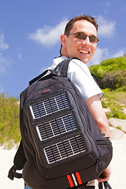 A man carrying a solar backpack, the solar panels can be used for recharging mobile phones and other electrical devices