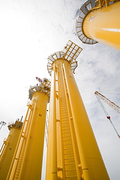 The yellow transition pieces that will hold the tower and turbine, that fit onto the monopile to hold the structure to the sea bed, Walney Offshore Wind Farm, Barrow in Furness, Cumbria, England, United Kingdom, Europe