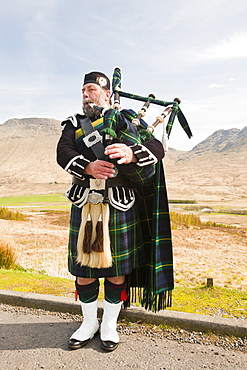 A Scottish piper in traditional dress busking on Rannoch Moor in Argyll, Scotland, United Kingdom, Europe