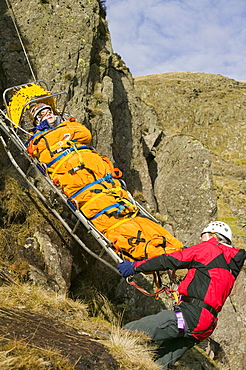 Members of Langdale Ambleside Mountain Rescue Team lower a stretcher down a crag as part of a training exercise, Lake District, Cumbria, England, United Kingdom, Europe