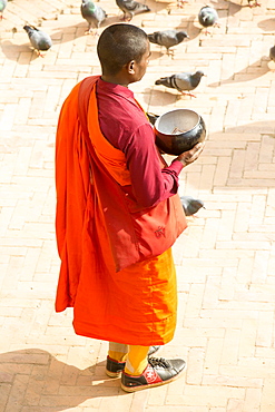 A Buddhist monk collecting donations at the Boudhanath Stupa, one of the holiest Buddhist sites in Kathmandu, Nepal, Asia