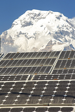 Solar photo voltaic panels being used to power a mobile phone mast at Ghandruk with Annapurna South in the background, Himalayas, Nepal, Asia