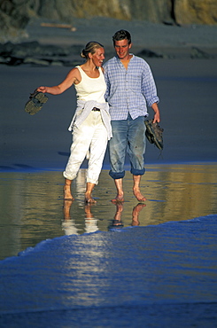 Couple walking at water's edge, Marloes Sands, West Wales, UK