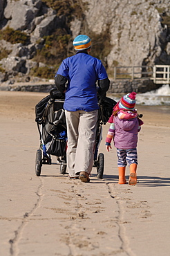 Mother pushing pushchair with children on beach, Broad Haven South, Stackpole, Pembrokeshire, Wales, UK, Europe