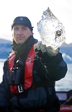 Tourist holding up a Glacier chunk.  Longyearbyne, Svalbard, Norway