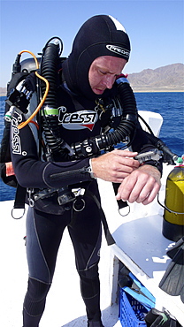 Diver on board dive boat checking equipment    