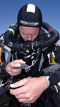 Diver on board dive boat checking equipment    