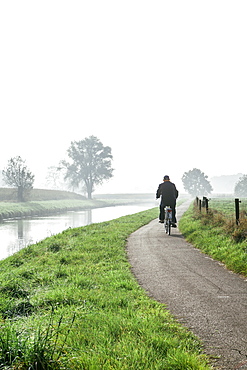 Man cycling on countryside cycle path next to the River Mark in autumn, Breda, North Brabant, The Netherlands (Holland), Europe