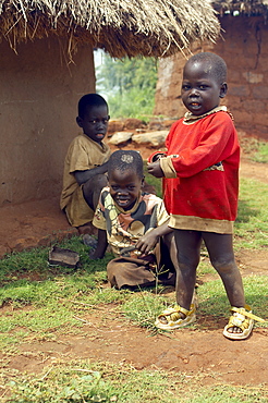 Three Children playing outside a mud hut.  A construction commonplace for housing in Gulu, Northwest Uganda,. Gulu Town, Uganda, East Africa