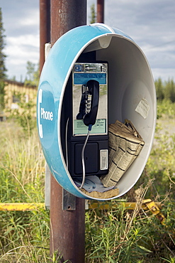 Retro style Public telephone, with weather-worn telephone directories and a post-it note stuck to the inside.  Roadside amenity  in the Alaskan Interior. The Interior, Alaska, USA