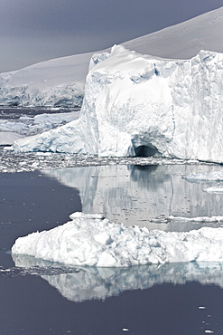 Icebergs and brash ice reflected in calm waters on the west side of the Antarctic peninsula, Antarctica.