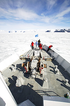 The National Geographic Endeavour breaking through fast ice in the Weddell Sea around the Antarctic Peninsula. Guests are on the bow watching the process.