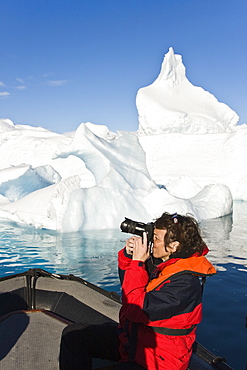 Lindblad Expeditions guest photographing icebergs from the Zodiac in Antarctica as part of expedition travel. NO MODEL RELEASES FOR THIS IMAGE.