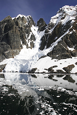 Reflections and snow covered mountains in Lemaire Channel in Antarctica.