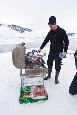 Guests from the Lindblad Expedition ship National Geographic Explorer enjoy a hot asado sandwich prepared by staff at BBQ on an ice floe near Adelaide Island, Antarctica