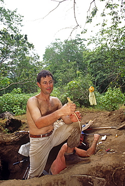 Cameraman, Mike Pitts, holding Komodo dragon hatchling.  Scene behind showing entrance in the megapode mound to film the underground nest.